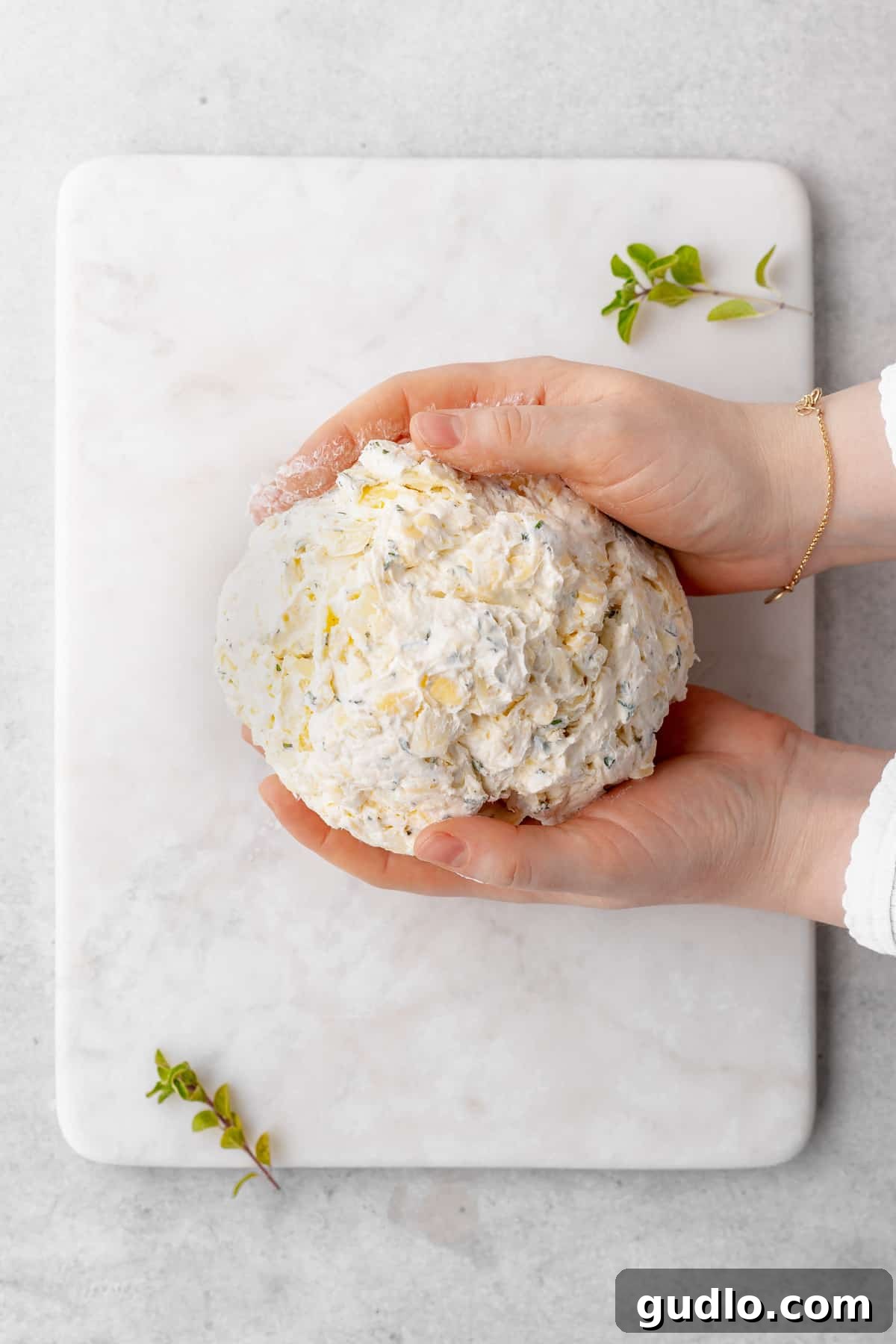 Shaping the Creamy Cheese Ball by Hand Hands carefully forming the chilled cheese mixture into a perfect ball shape.