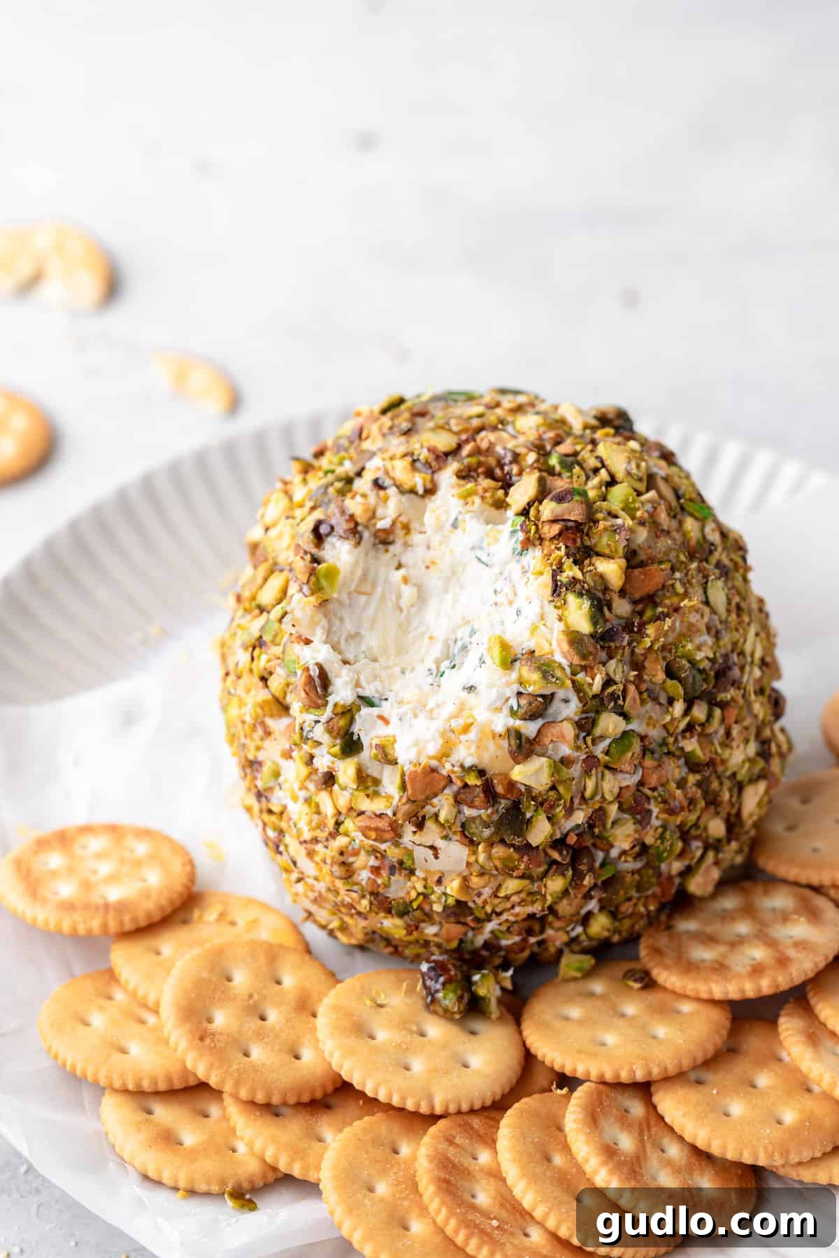 Creamy Cheese Ball Ready for Dipping with Crackers A freshly made cheese ball with a portion already dipped out, surrounded by crackers.