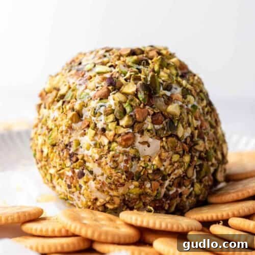 Ready-to-Serve Herb and Pistachio Cheese Ball Finished cheese ball on a plate, surrounded by various crackers and ready to be served.