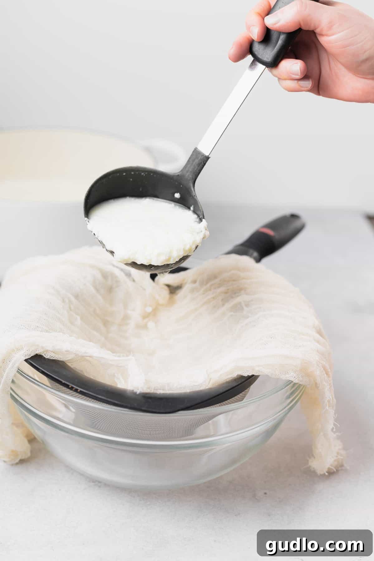 Crafting Fresh Ricotta at Home 4 A ladle gently strains fresh ricotta curds from the whey into a cheesecloth-lined colander.