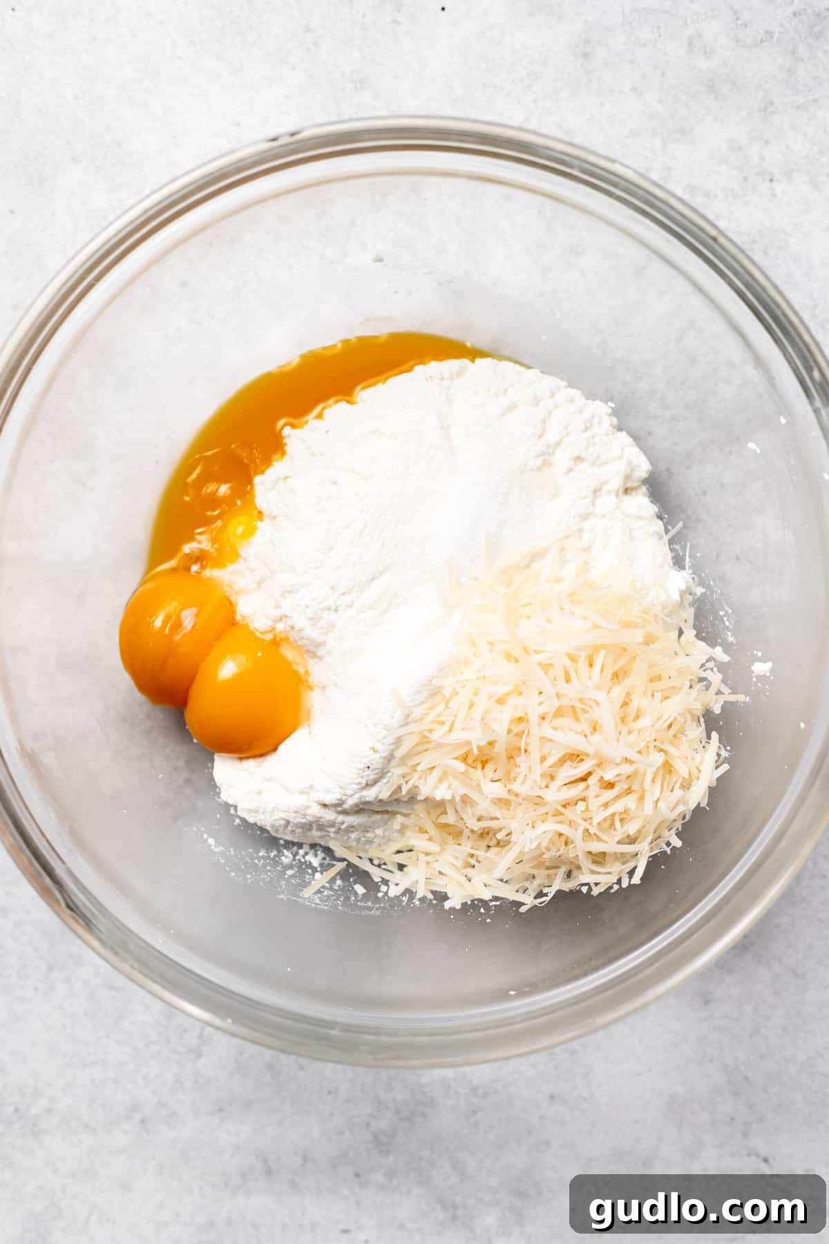 Mixing Ricotta Gnocchi Ingredients Gently Ricotta gnocchi ingredients, including ricotta, egg yolks, and grated cheese, thoughtfully placed in a bowl, ready for the gentle mixing process.