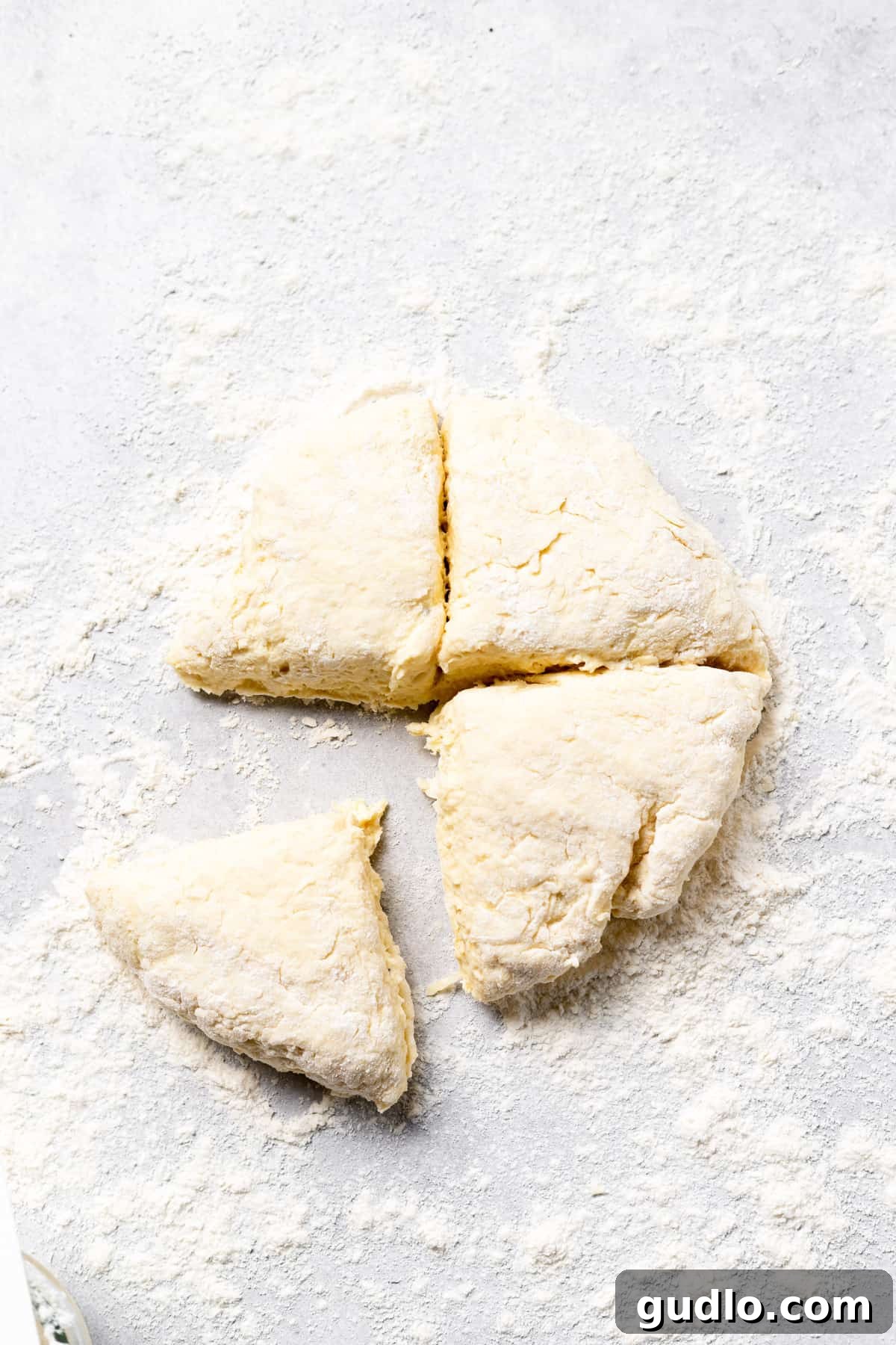 Dividing Ricotta Gnocchi Dough for Shaping Ricotta gnocchi dough, neatly divided into four equal portions on a lightly floured surface, ready for rolling into logs.