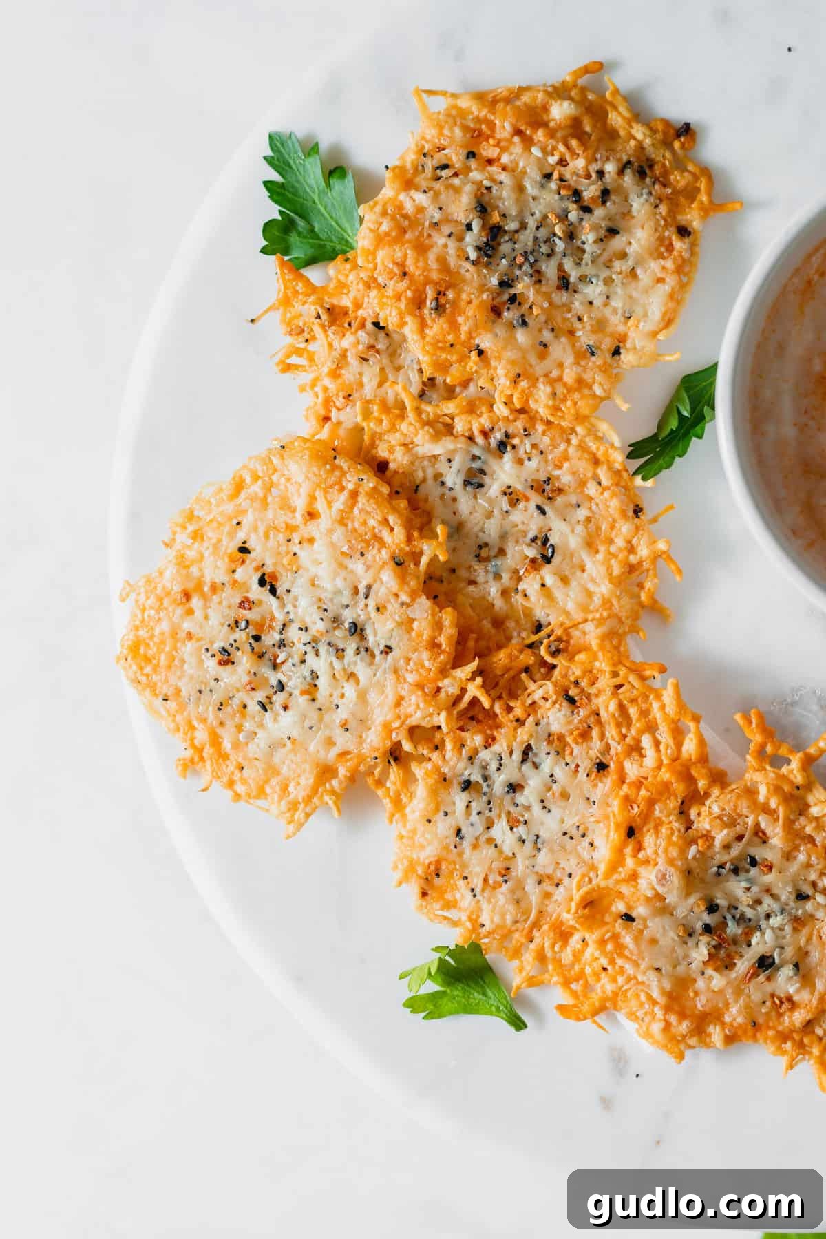 Golden brown parmesan cheese crisps perfectly arranged on a white plate, ready to be enjoyed as a low-carb snack or garnish.