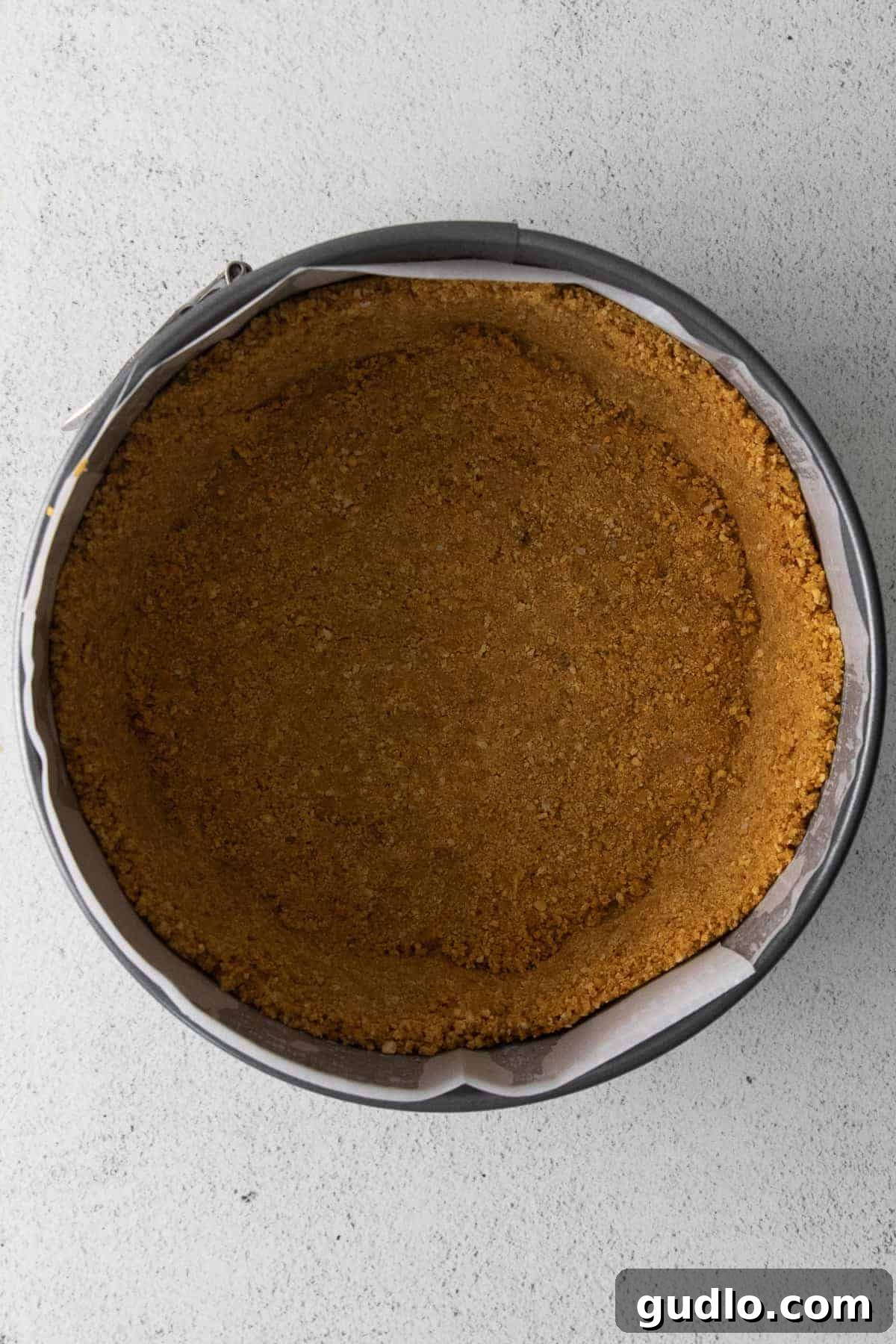 Crafting the Perfect Graham Cracker Crust A perfectly pressed graham cracker crust lining a 7-inch springform pan, ready for the cheesecake filling.