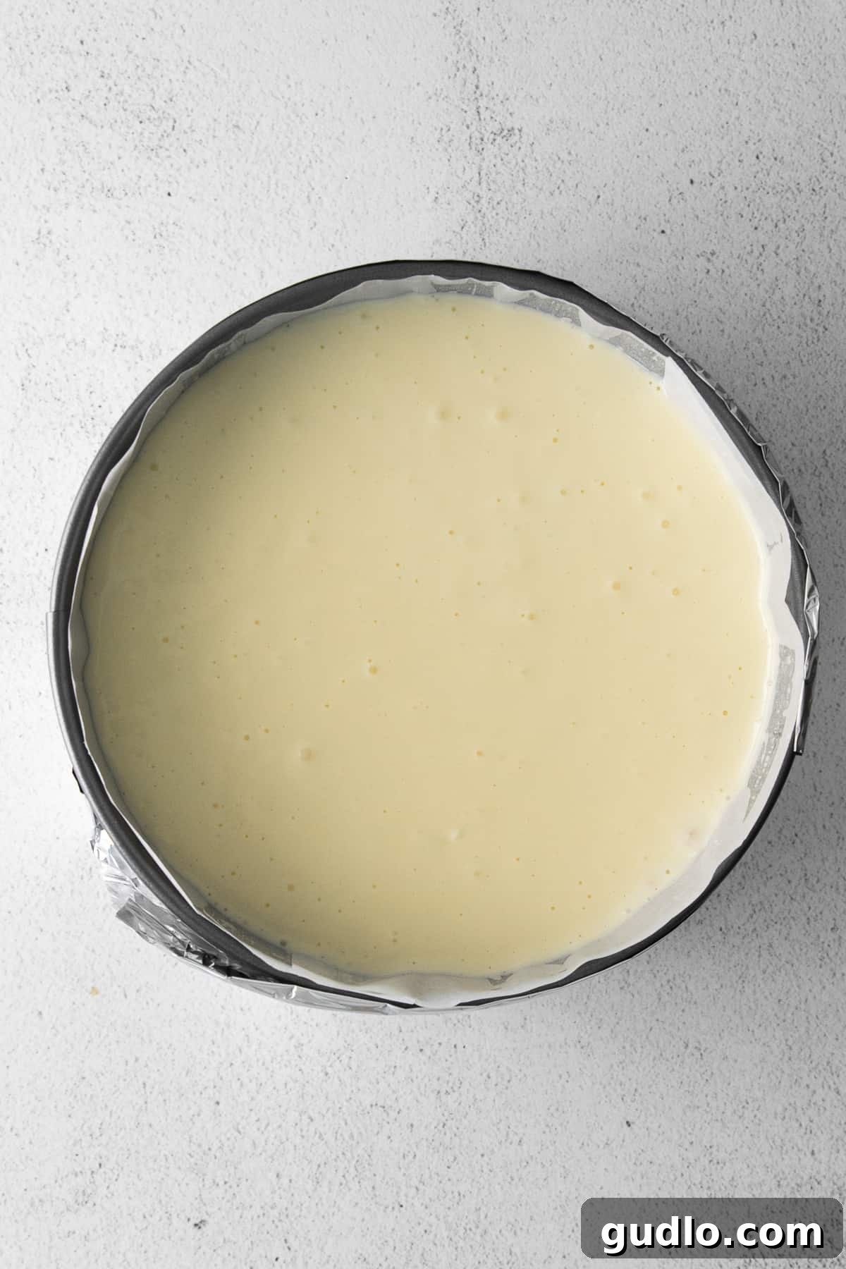 Readying the Cheesecake for Pressure Cooking Smooth, raw cheesecake batter poured into a graham cracker crust-lined springform pan, ready for the Instant Pot.