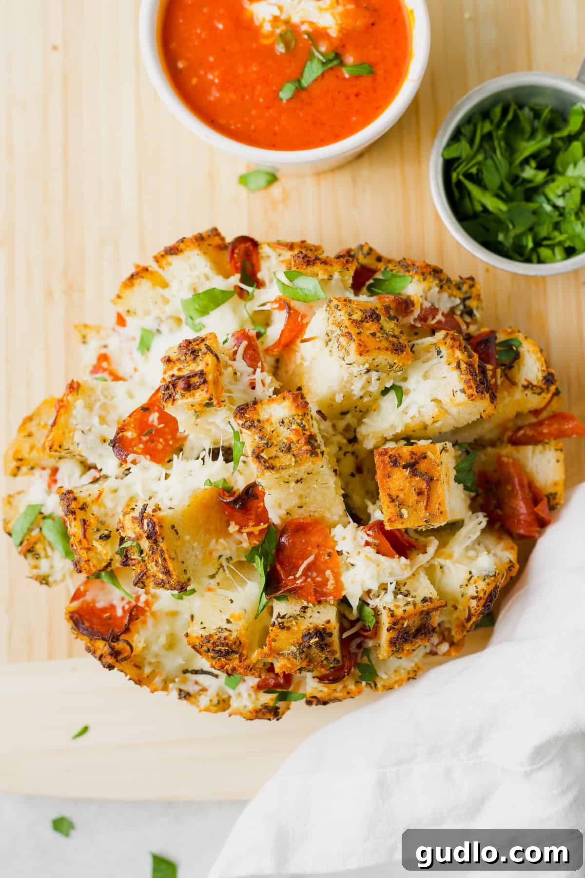 Golden brown pizza stuffed pull apart bread on a wooden cutting board, ready to be served