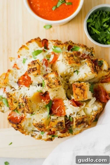A hand pulling a piece of cheesy pizza bread