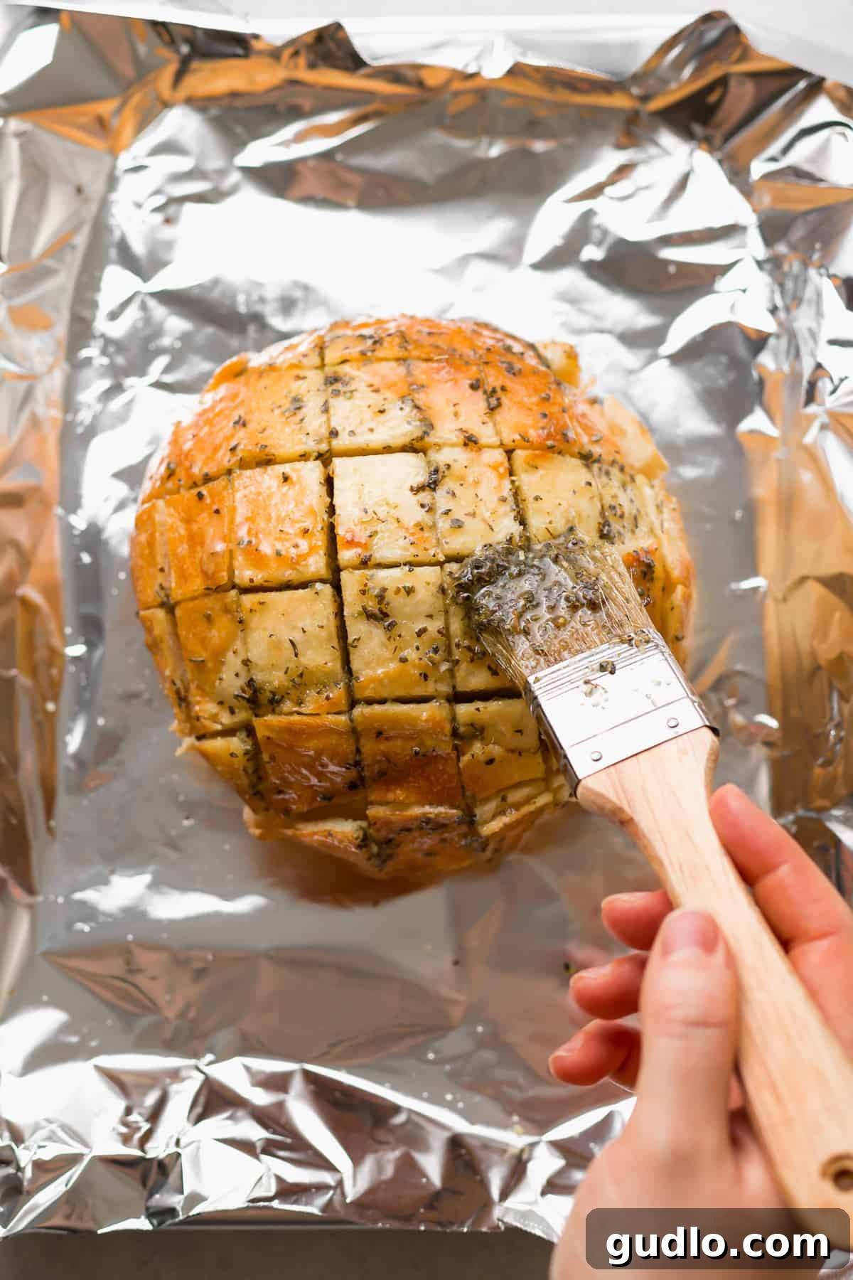 A pastry brush applying garlic butter evenly onto the sliced sourdough bread