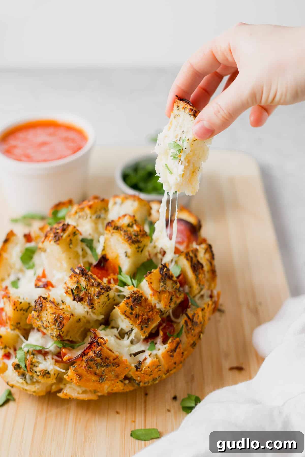 Hand pulling a cheesy, pepperoni-filled slice from the pizza pull apart bread loaf