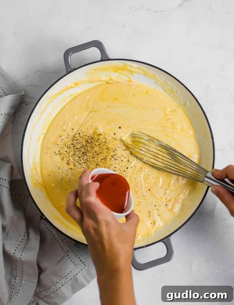 The Definitive Mac and Cheese Sauce 2 Creamy cheese sauce for mac and cheese simmering in a rustic Dutch oven, ready to be mixed with pasta