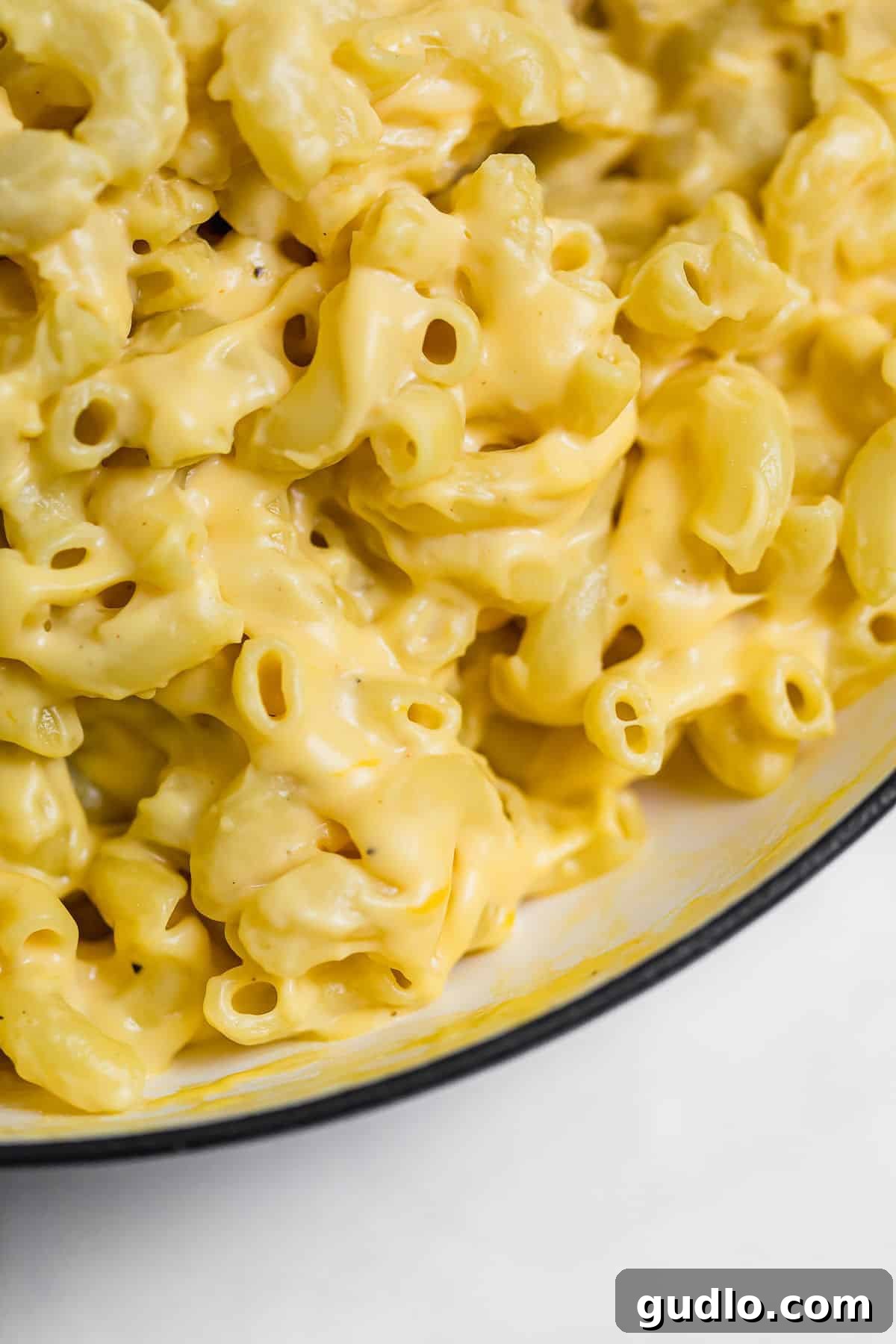 The Definitive Mac and Cheese Sauce 6 Delicious, creamy mac and cheese sauce generously coating perfectly cooked macaroni noodles in a serving bowl, garnished with fresh herbs