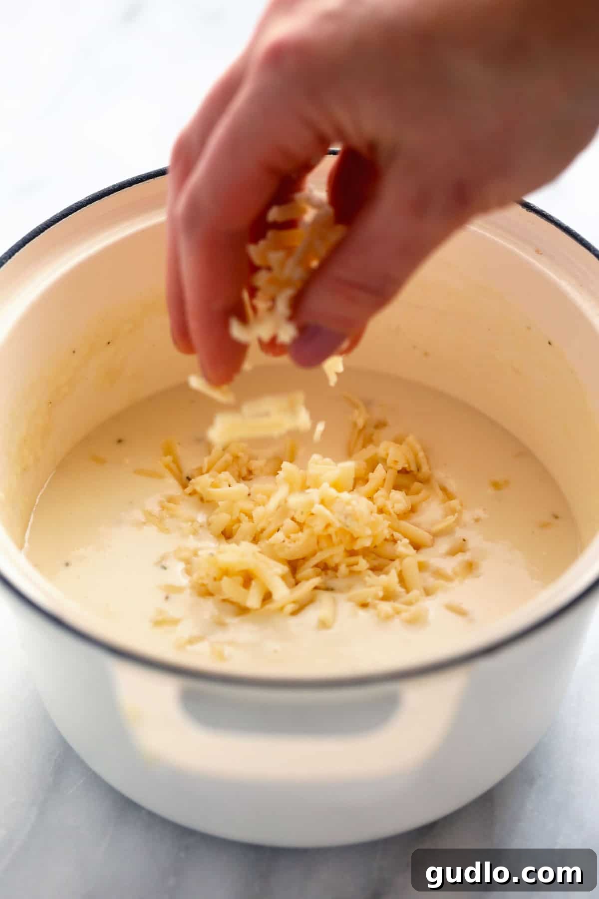 Watch as freshly shredded cheese transforms into a rich, velvety sauce for your baked mac and cheese. shredded cheese being melted into a cheese sauce for baked mac and cheese