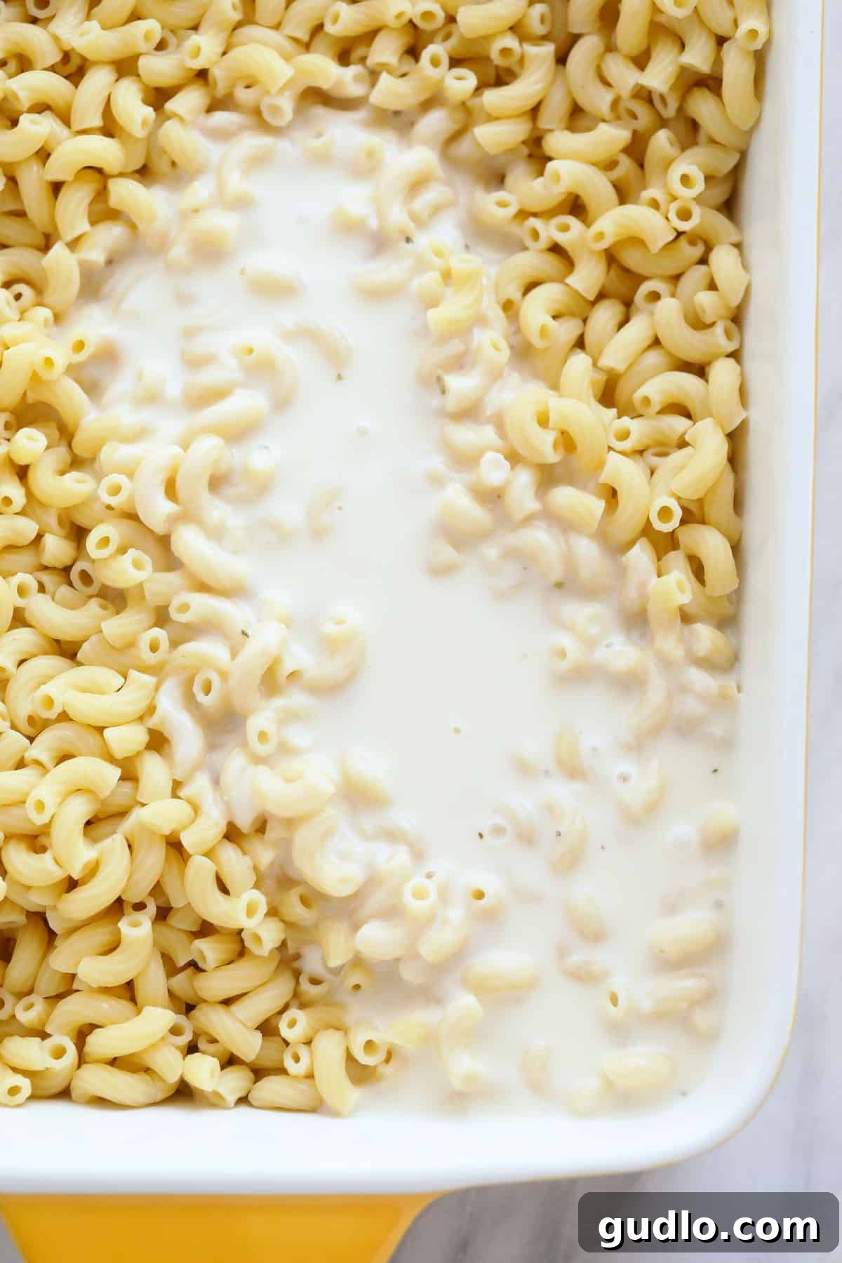 The ultimate comfort food: baked mac and cheese smothered in rich, creamy sauce. cheese sauce poured over baked mac and cheese in a casserole dish