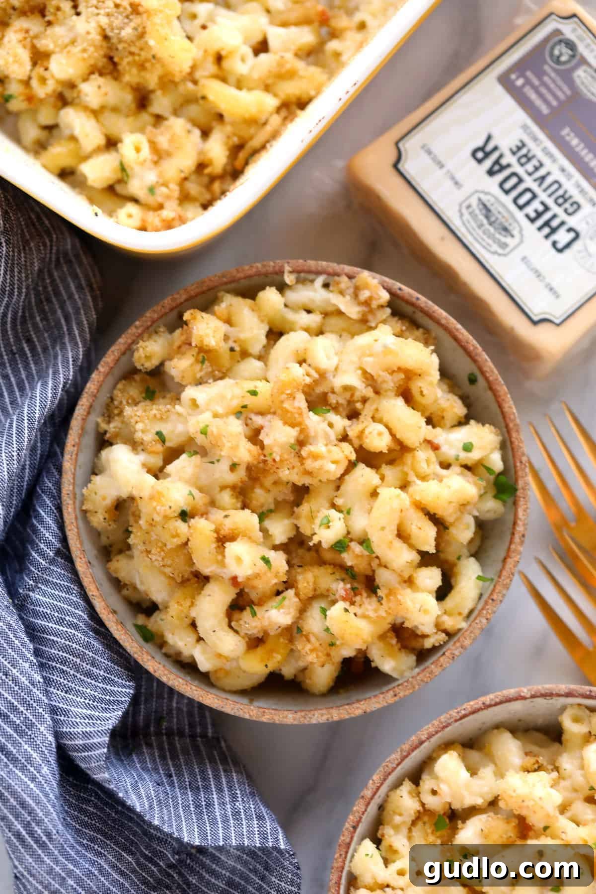 A bowl of delicious baked mac and cheese, ready to be devoured, garnished with fresh parsley. baked mac and cheese in a bowl topped with a delicious breadcrumb topping and fresh parsley