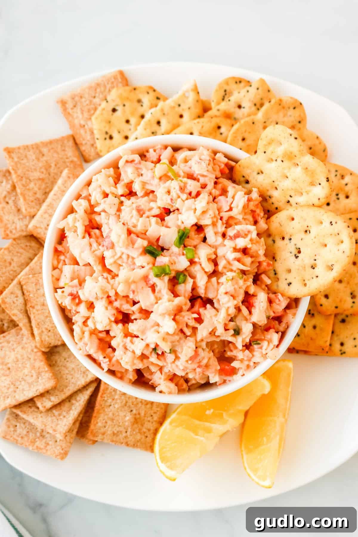 Cool & Creamy Crab Dip 2 A beautifully presented cold crab dip in a rustic bowl, surrounded by an assortment of crackers and fresh herbs, ready to be served at any occasion.