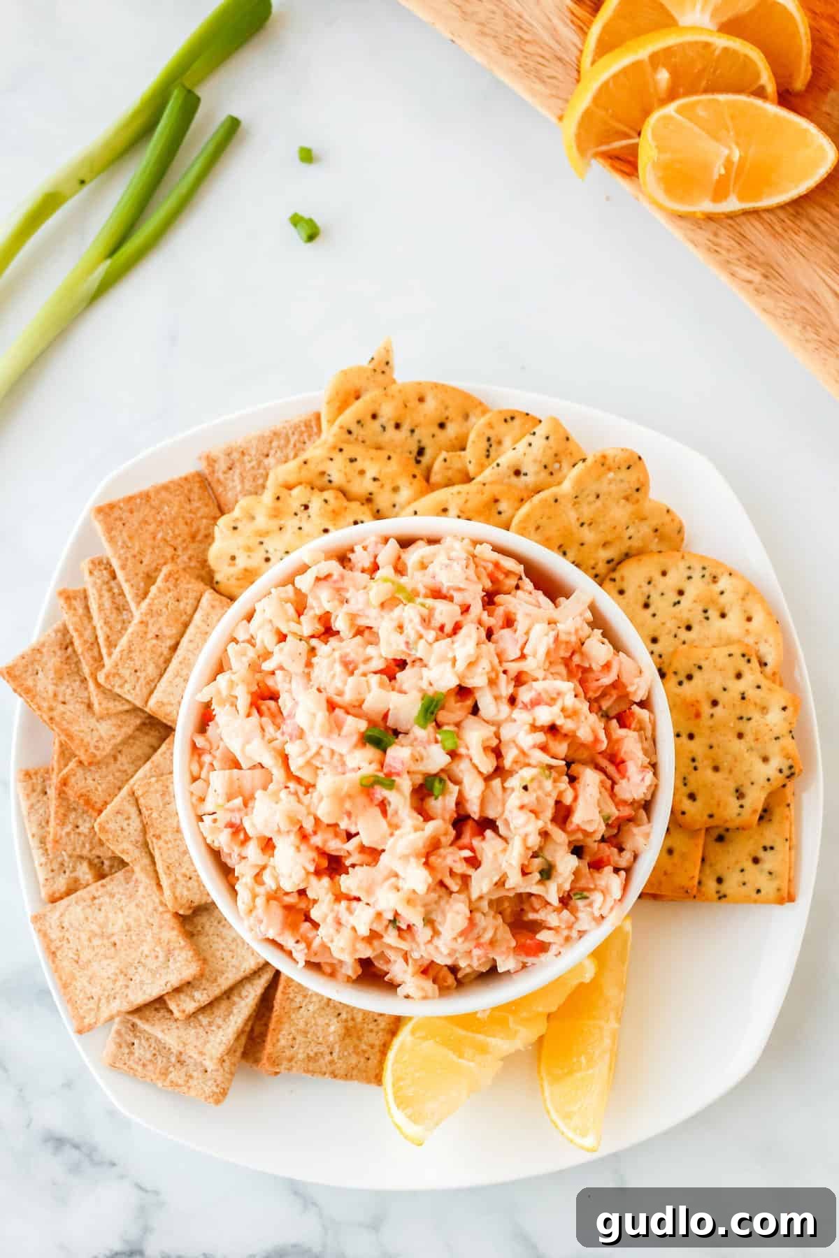 Cool & Creamy Crab Dip 5 A generous bowl of cold crab dip, perfectly garnished and surrounded by an array of crunchy crackers, inviting guests to dig in.