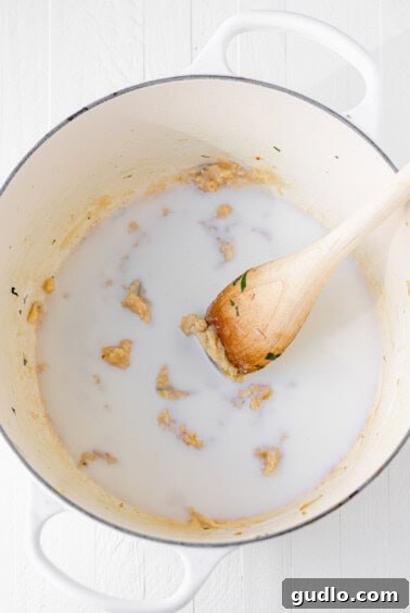 The process of preparing a roux, showing milk being added to the flour and butter mixture in a pot, being whisked to thicken.