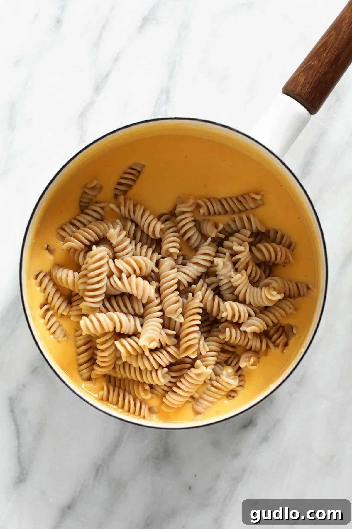 The Ultimate Gluten-Free Mac and Cheese 5 Gluten-free noodles generously coated in a rich, creamy, homemade cheese sauce, glistening in a pot.