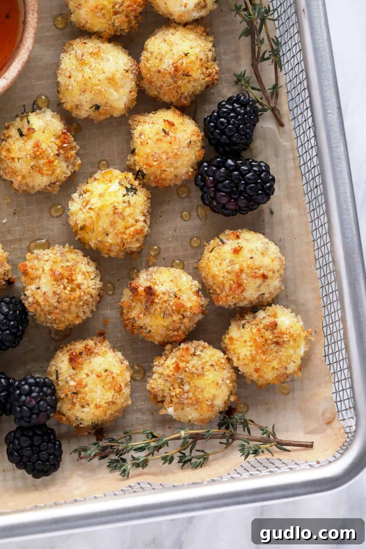 A basket filled with golden-brown baked goat cheese balls, ready to be served as an appetizer.