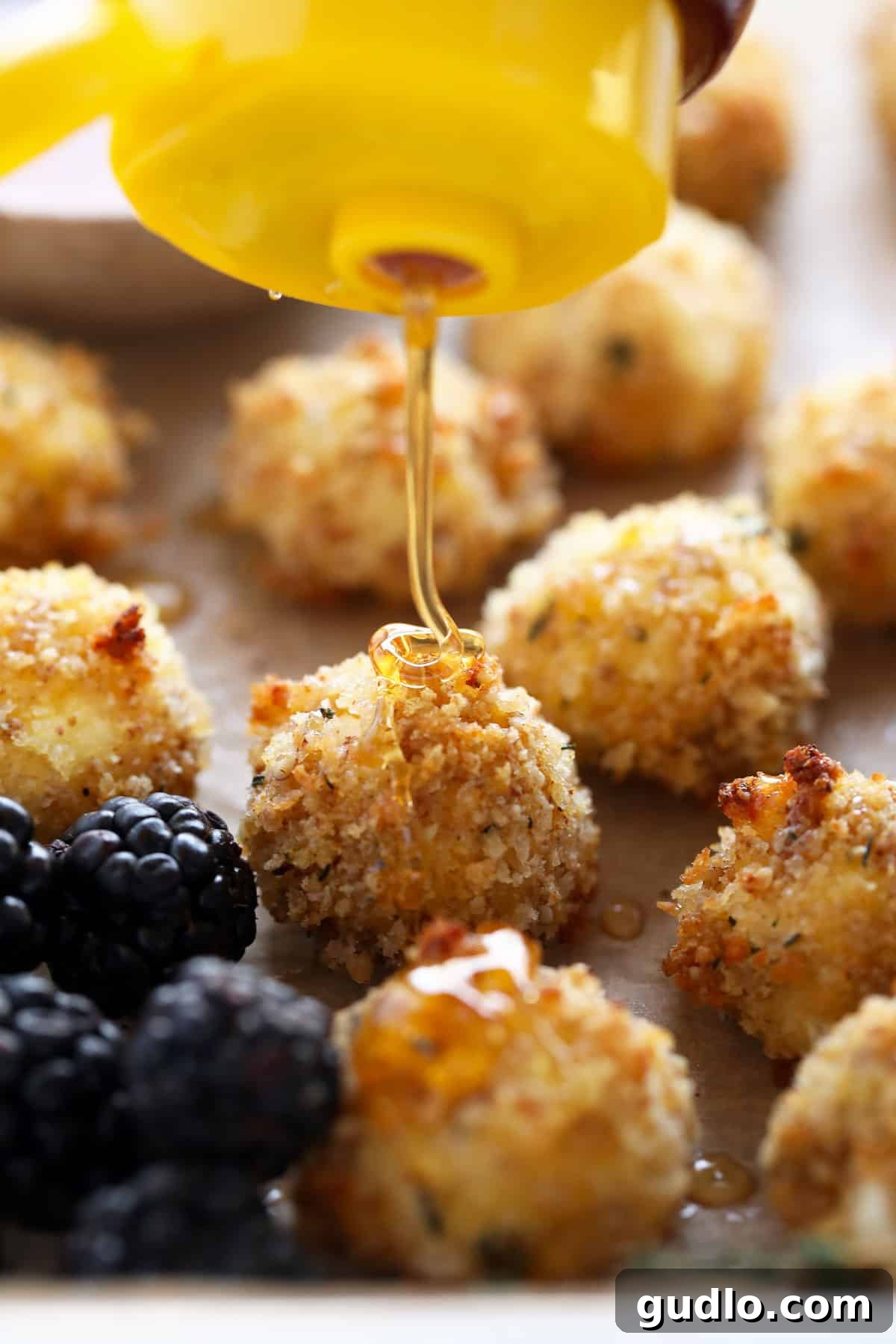 A stack of crispy baked goat cheese balls on a plate, garnished with fresh thyme leaves.