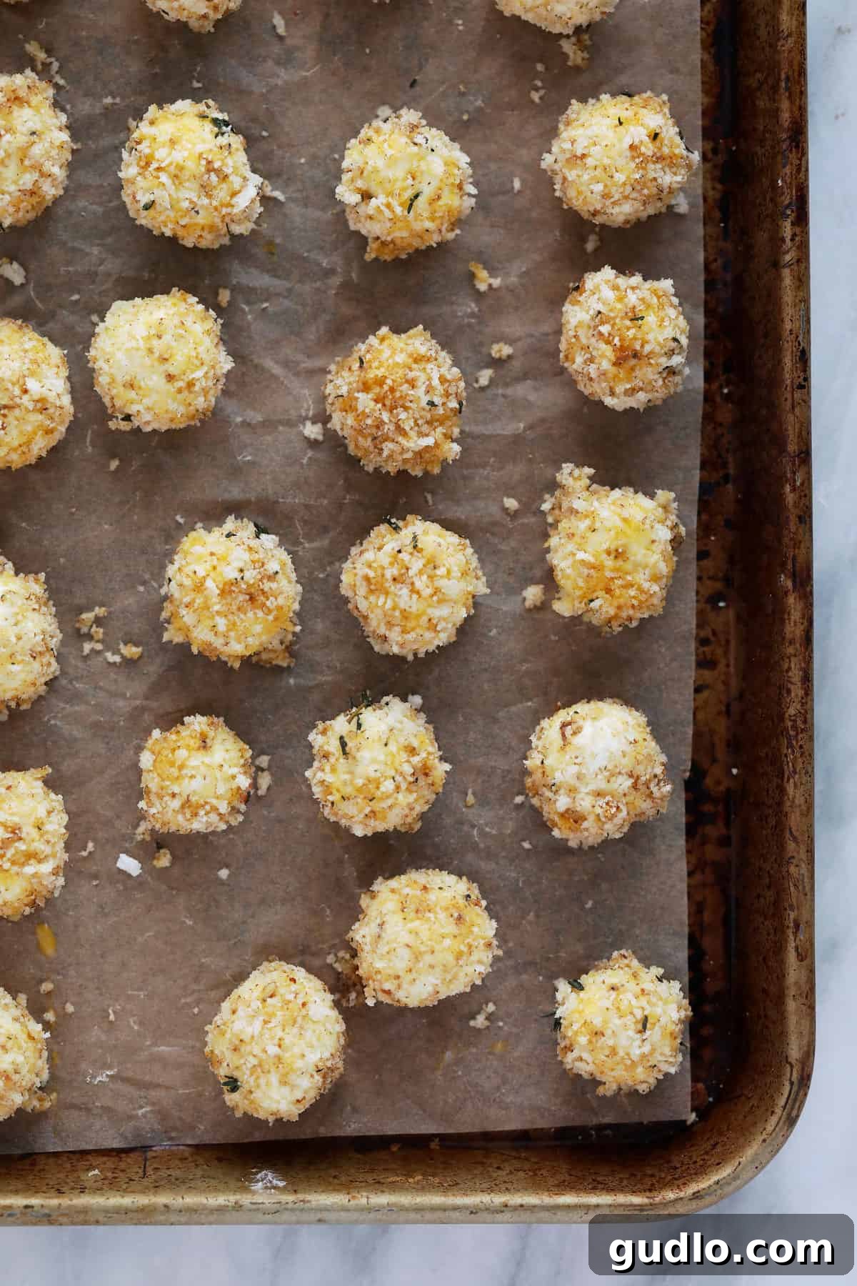 A plate of baked goat cheese balls served with a small bowl of honey sriracha dip on the side.