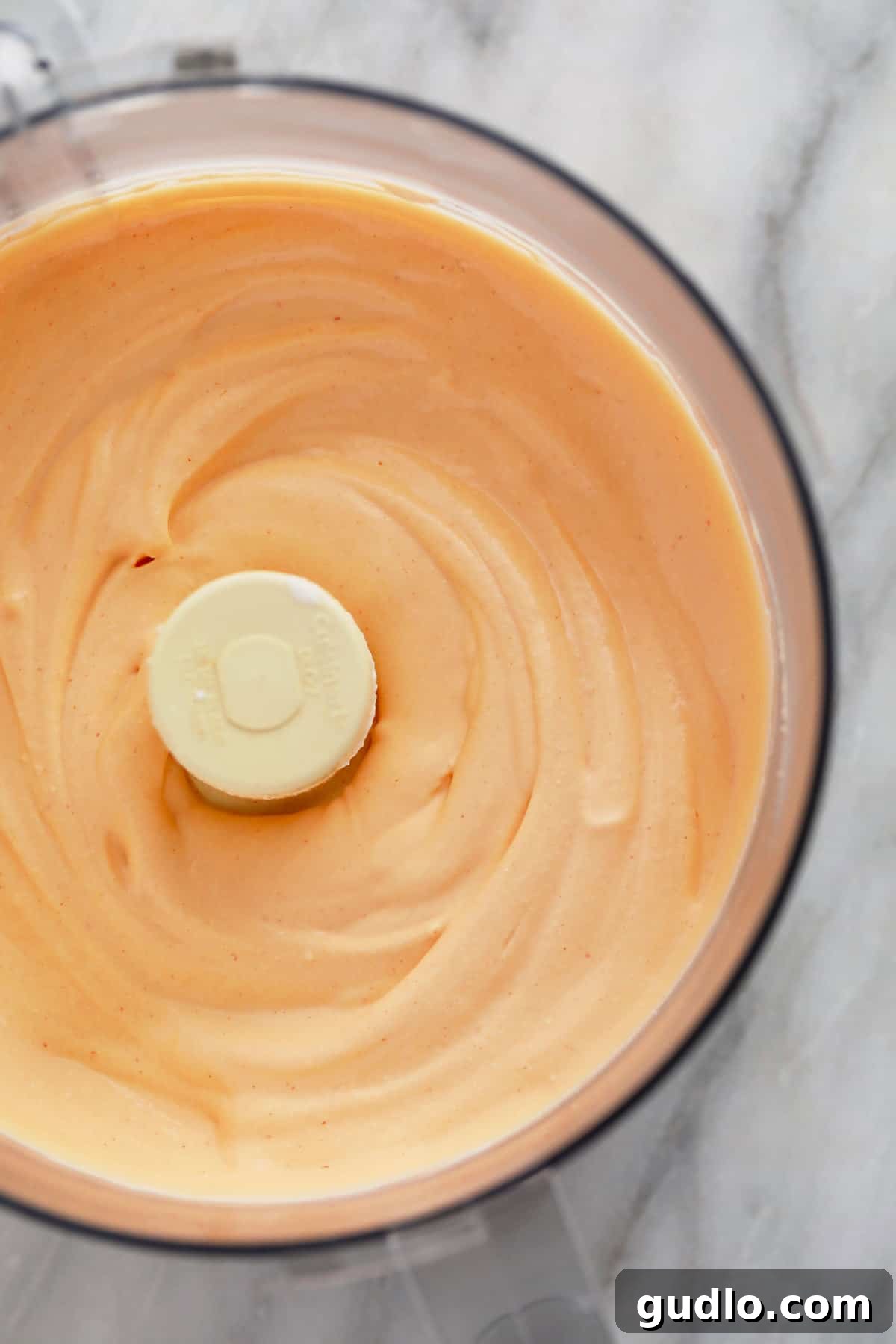 Perfectly Blended Buffalo Whipped Cottage Cheese Dip The vibrant orange buffalo whipped cottage cheese dip, perfectly blended to a smooth, creamy consistency, resting inside the food processor bowl after all ingredients have been incorporated.