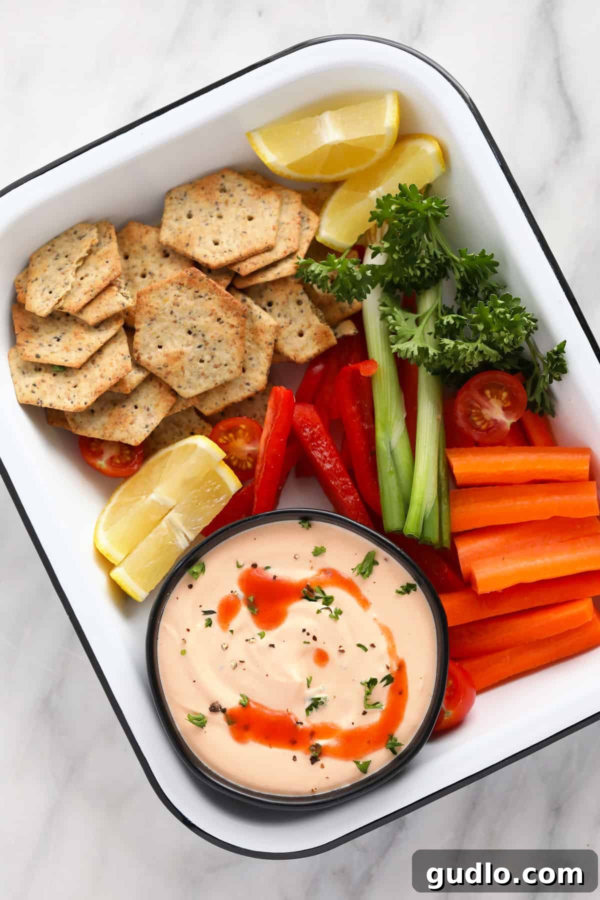 Buffalo Whipped Cottage Cheese Dip Ready for Dipping A beautifully presented serving bowl of buffalo whipped cottage cheese dip, garnished with cracked black pepper, surrounded by a colourful and inviting spread of fresh vegetables and crispy crackers, ready to be enjoyed as a vibrant appetizer.
