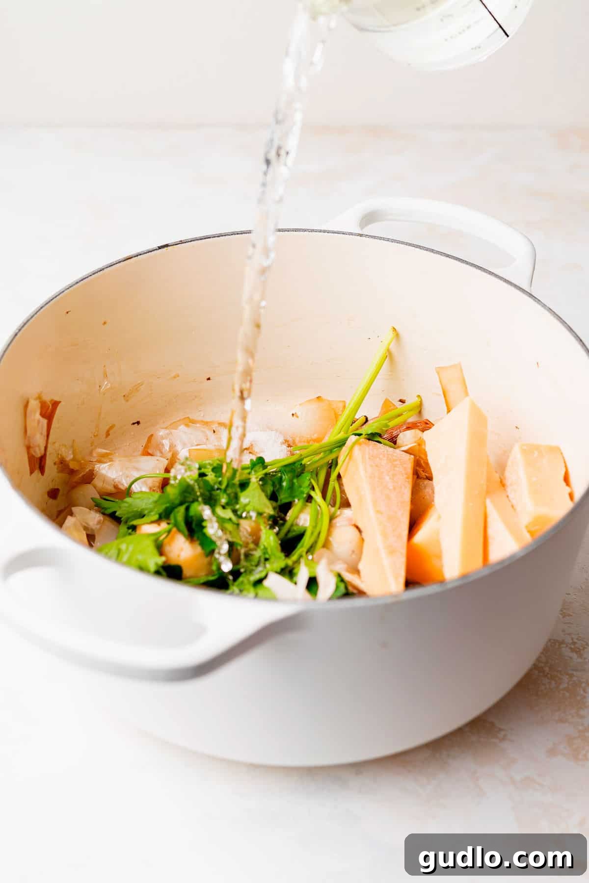 Fresh Ingredients for Parmesan Broth Ingredients for homemade parmesan broth, including parmesan rinds, onions, mushrooms, and herbs, gathered in a stock pot, ready for cooking.