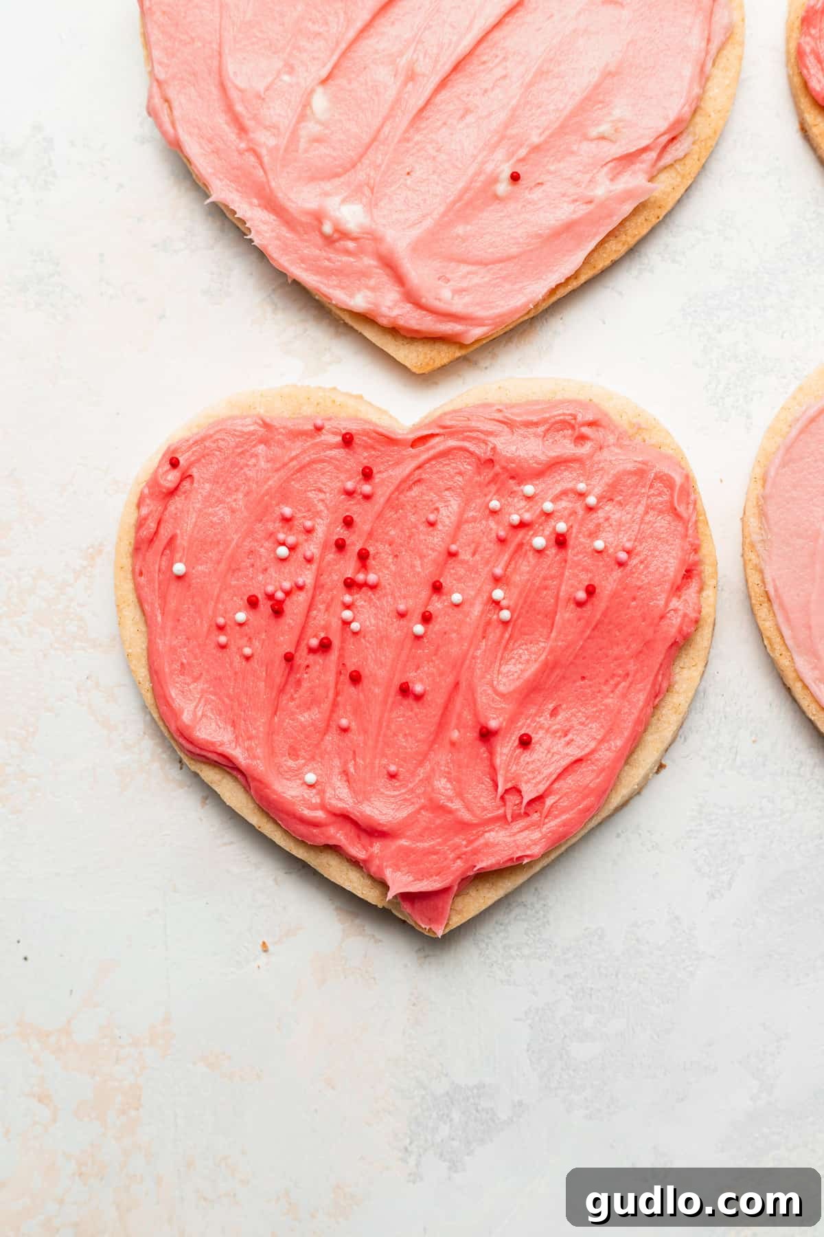 Yummy heart cookies for Valentine's Day with a homemade cream cheese frosting. These heart shaped cookies are so fun to bake as a family and made with our famous cream cheese sugar cookie dough. Enjoy! Irresistible cream cheese heart cookies with vibrant pink frosting and playful sprinkles, perfect for Valentine's Day.