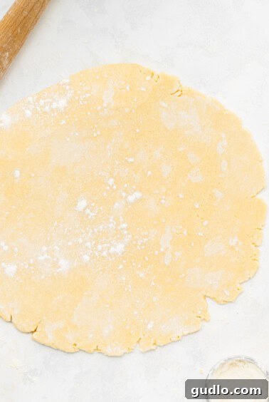 Heart-shaped cookies being cut from pastry dough using a rolling pin and cookie cutters.