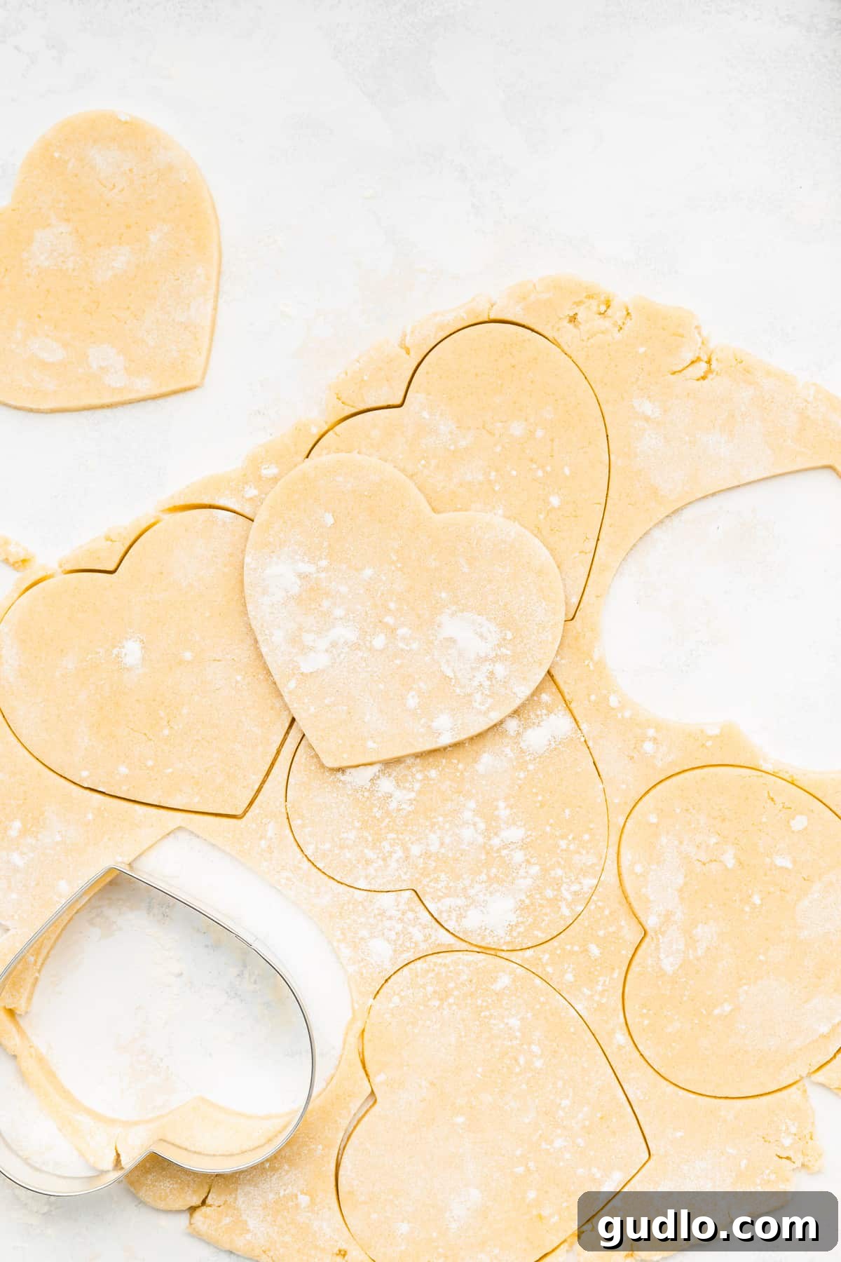 Yummy heart cookies for Valentine's Day with a homemade cream cheese frosting. These heart shaped cookies are so fun to bake as a family and made with our famous cream cheese sugar cookie dough. Enjoy! Perfectly cut cream cheese heart cookie dough, ready for the oven, showcasing clean edges from the cookie cutter.