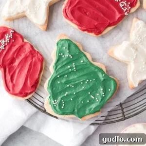 Velvety Cream Cheese Cookie Icing 2 A festive arrangement of Christmas sugar cookies adorned with white and red cream cheese icing, resting on a cooling rack.