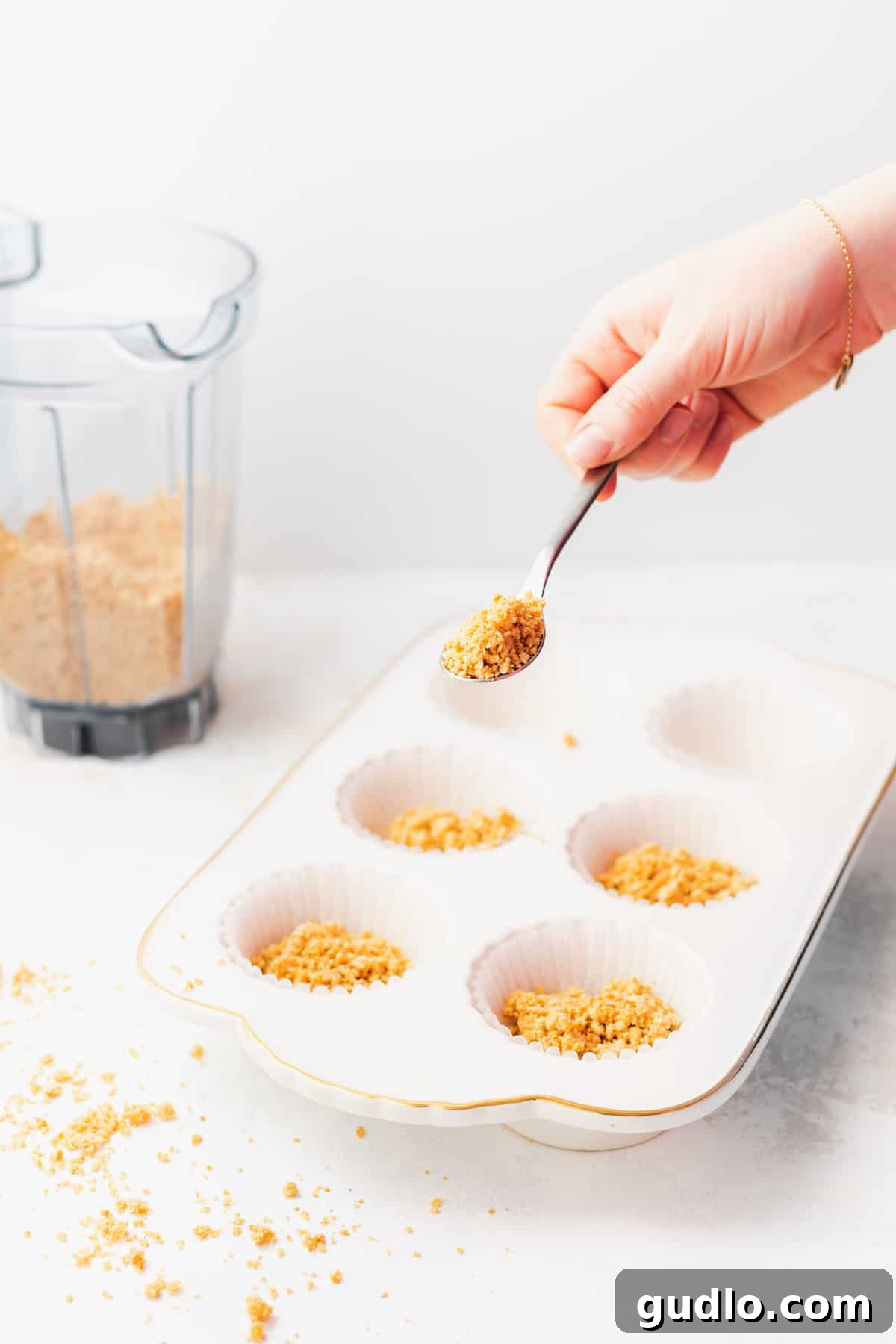 These pistachio pie cups are an individual size pistachio pie you'll absolutely LOVE! Made with a pistachio cheesecake filling and an easy graham cracker crust. Don't forget the dollop of whip on top! Graham cracker crust mixture being carefully spooned into muffin liners, ready for pressing.