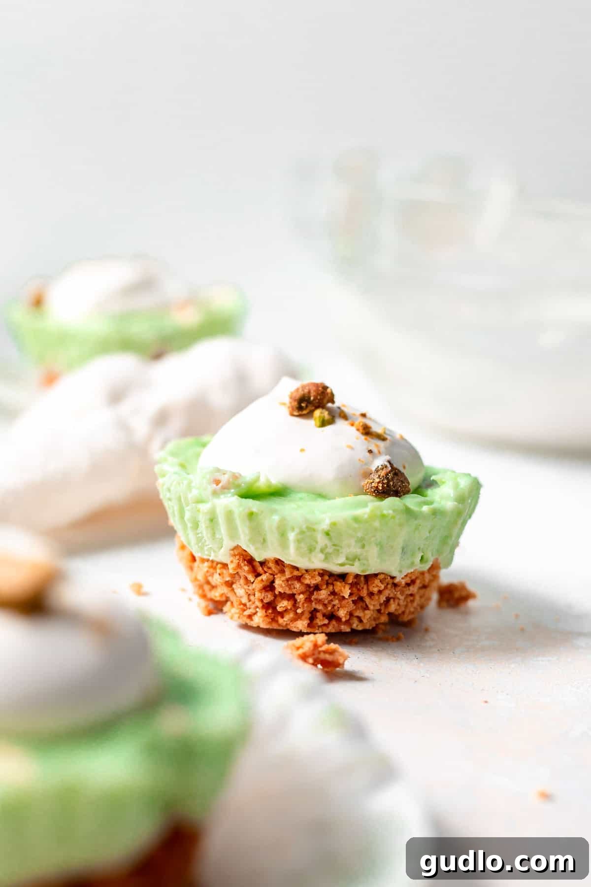 Pistachio pie cup with a graham cracker crust, ready to be enjoyed A single pistachio pie cup with a graham cracker crust, topped with whipped cream and crushed pistachios, ready to be enjoyed.