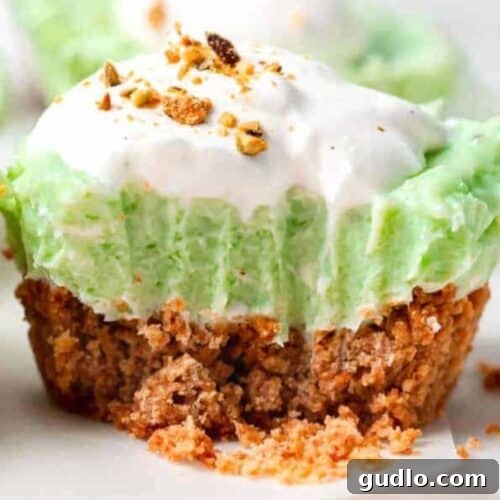 A close up of a green pistachio pie with whipped cream on top in small cups, showcasing the delicate topping.
