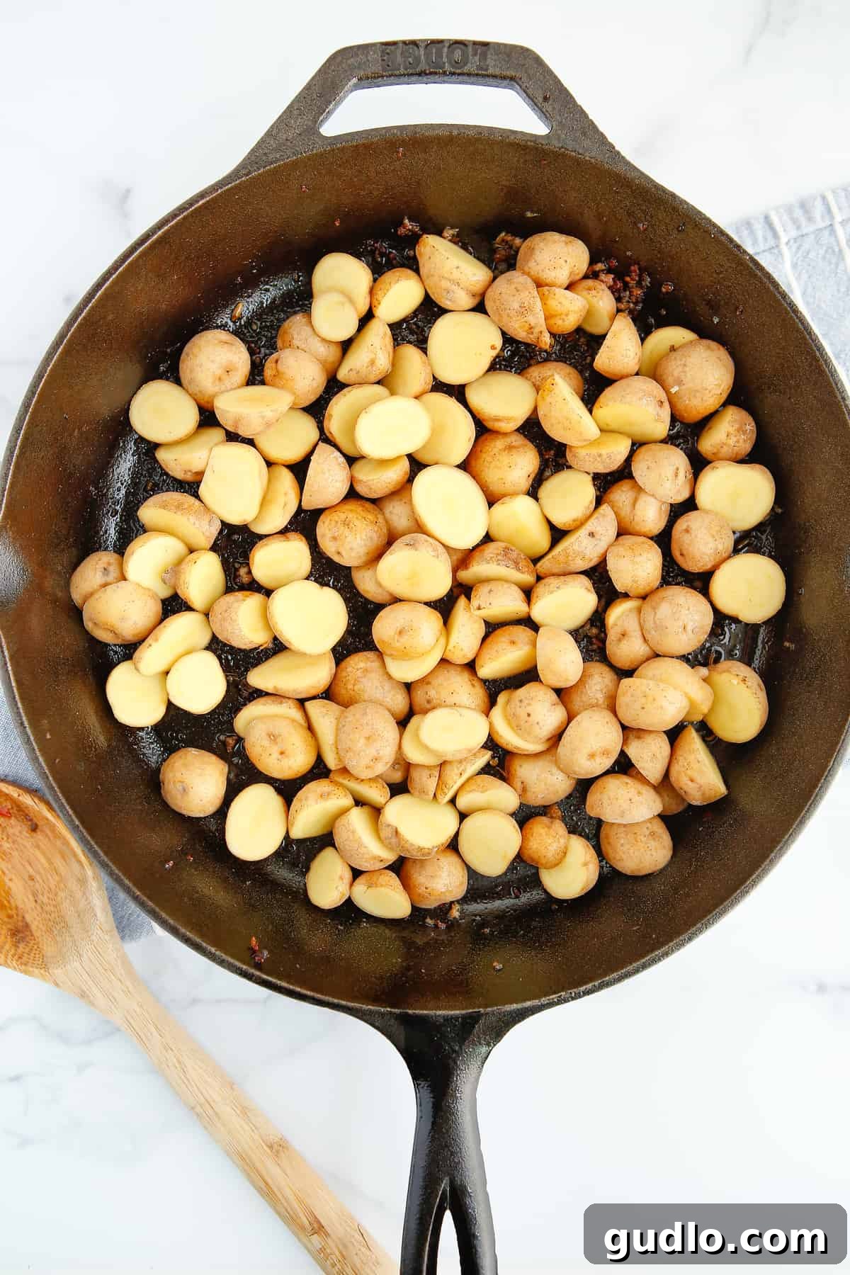 Sizzling Skillet Breakfast Potatoes 6 Halved baby potatoes cooking in a cast iron pan, ready to be simmered.