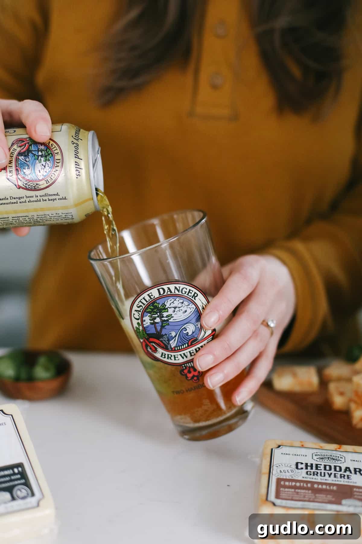 Refreshing Castle Danger Cream Ale: A Minnesota Craft Beer Gem Castle Danger Cream Ale being poured into a glass, garnished with fresh green olives on the side, hinting at a perfect pairing.