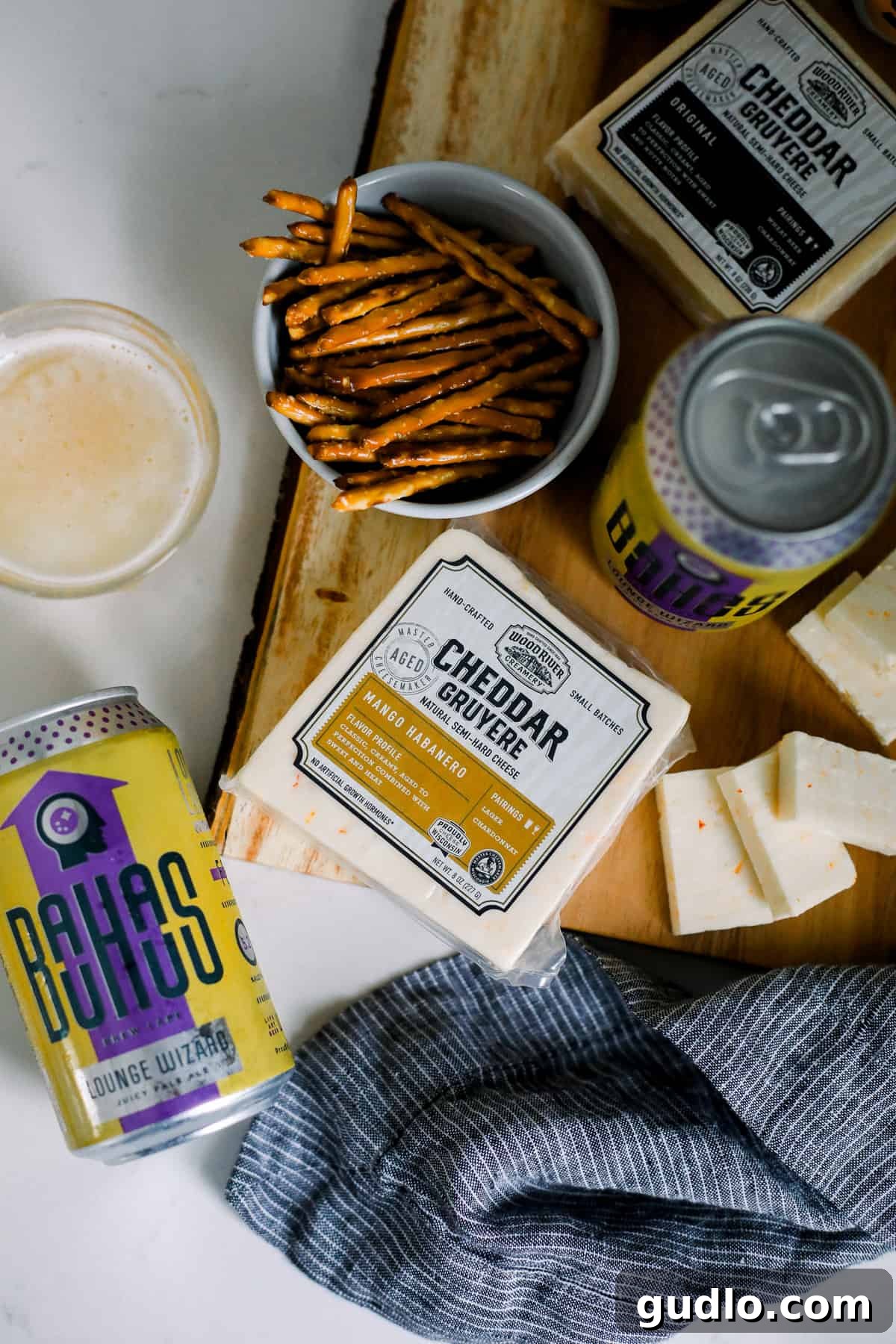 Sweet & Spicy Perfection: Mango Habanero Cheese and Juicy Pale Ale Wood River Creamery Mango Habanero cheese paired with pretzel sticks and a glass of Bauhaus Brew Labs Lounge Wizard Juicy Pale Ale on a rustic board.