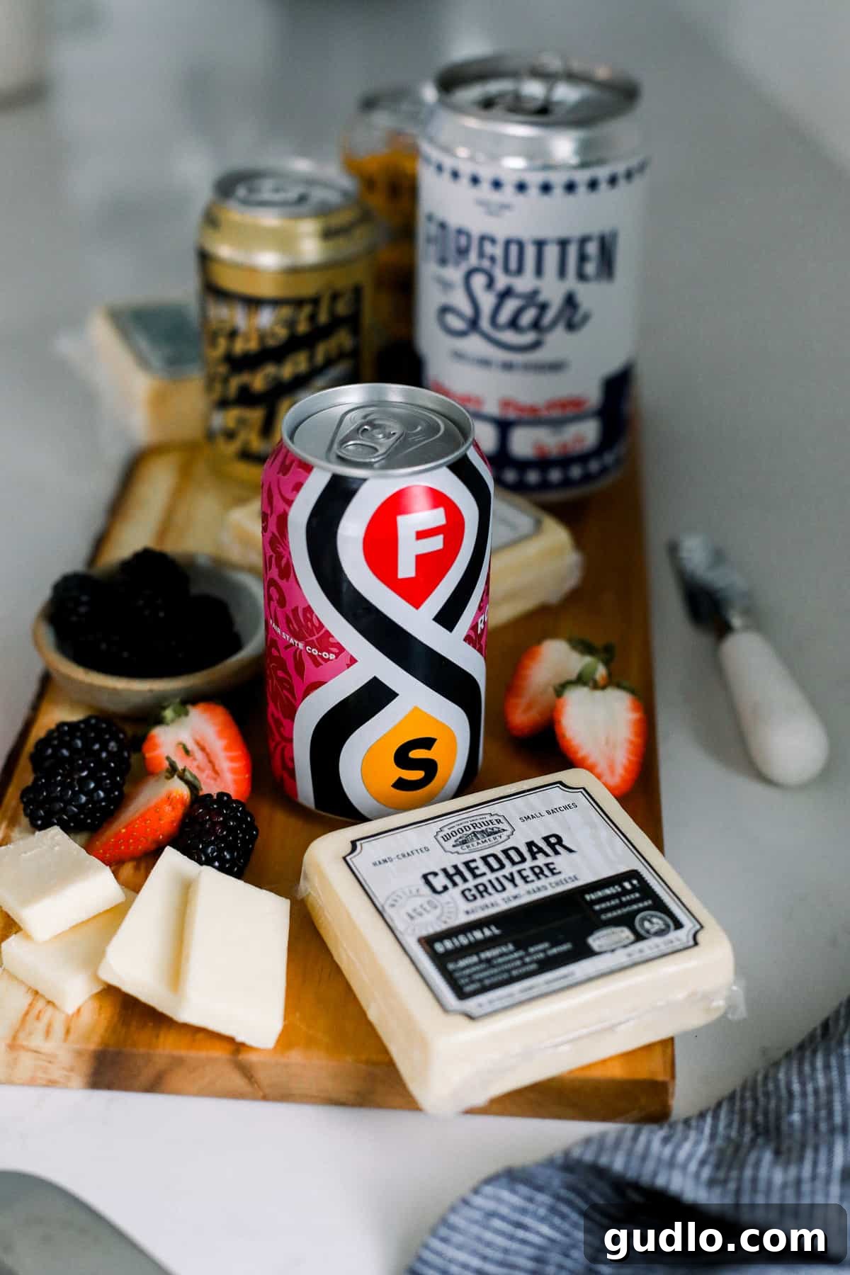Original Cheese & Hibiscus Sour: A Bright & Fruity Pair Wood River Creamery Original cheese slices with fresh berries, accompanied by a glass of Fair State Brewing Roselle Hibiscus Kettle Sour.
