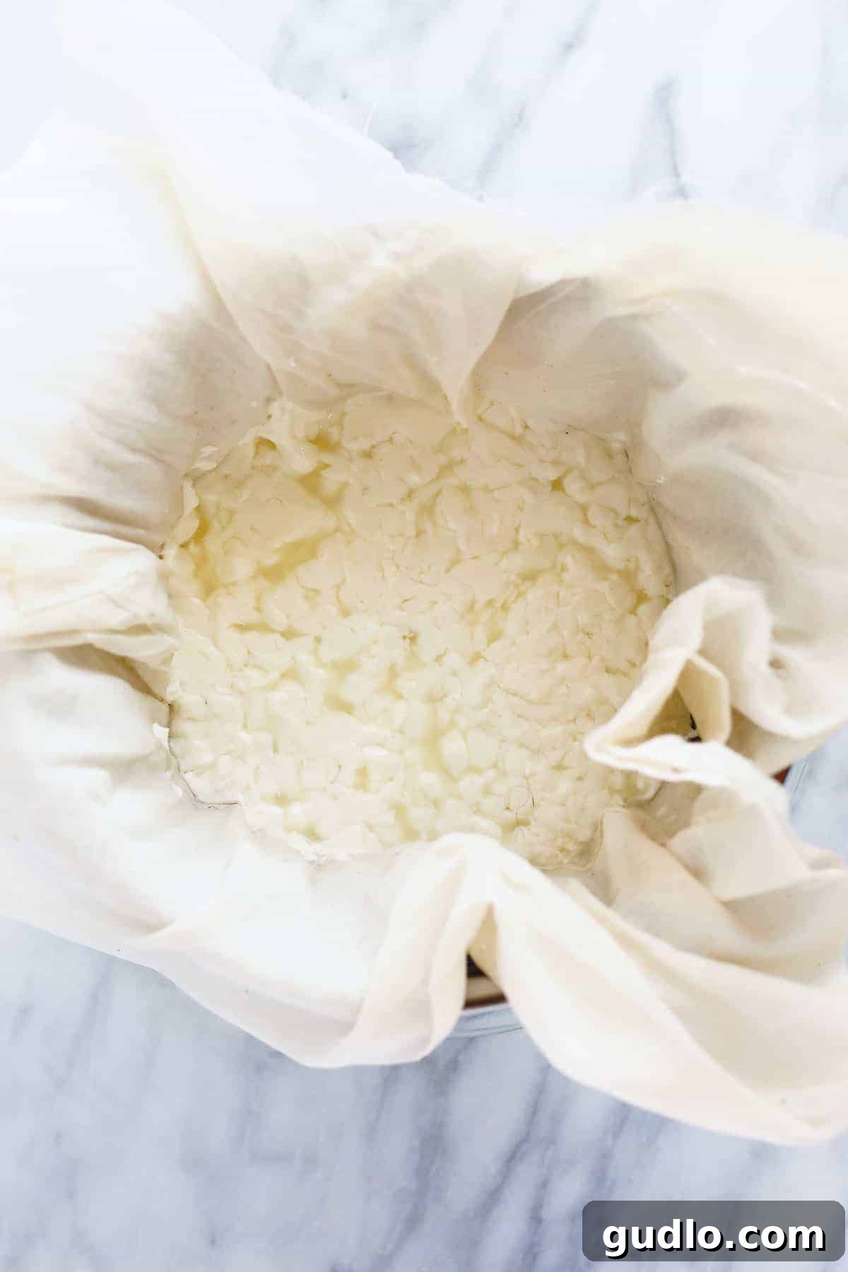 The Art of Making Queso Fresco at Home 7 Queso fresco curds resting in a cheesecloth-lined colander for drainage.
