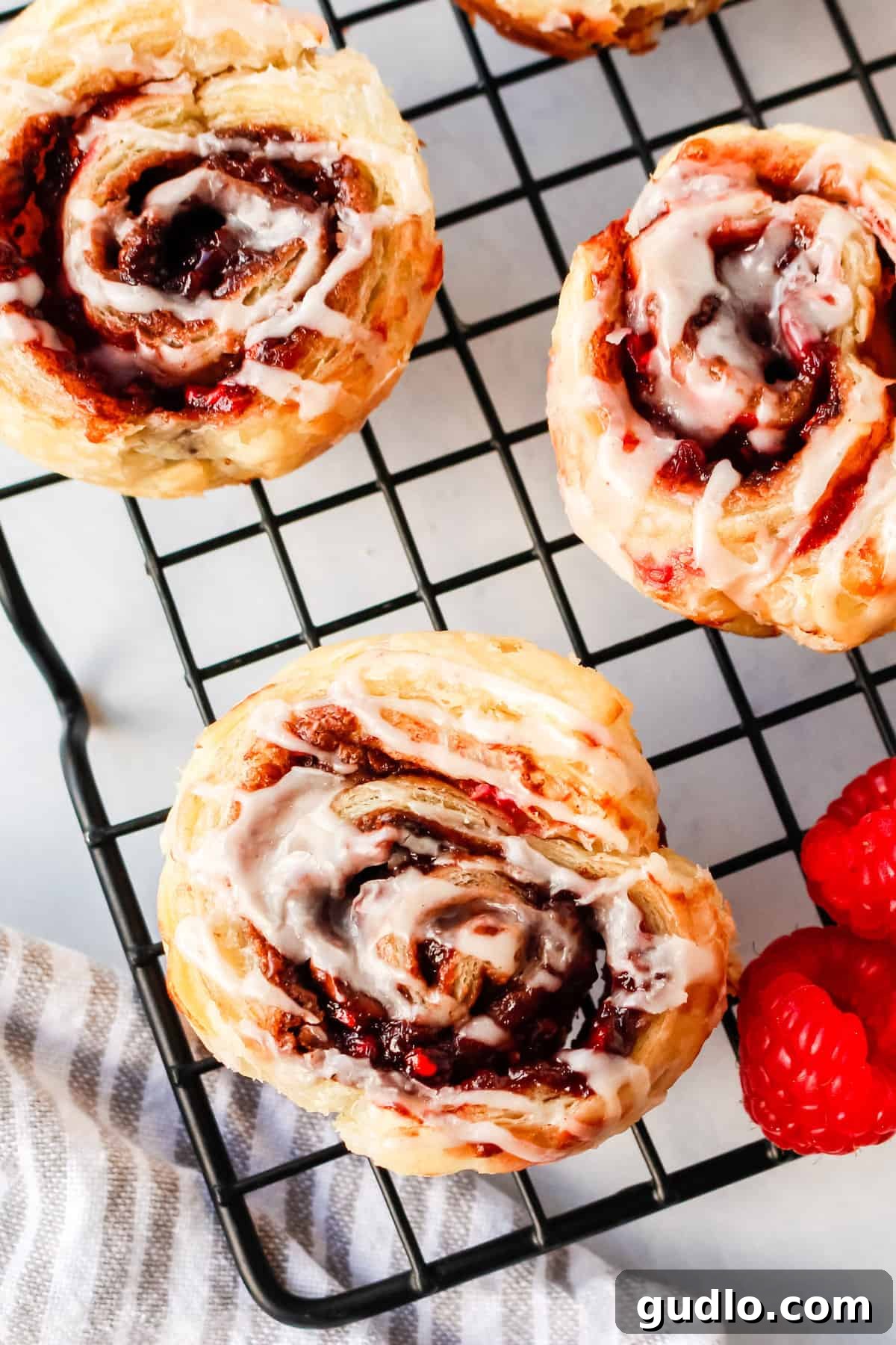 Start your day with these delicious Chocolate Raspberry Cinnamon Rolls that use store-bought dough and a few simple ingredients paired with a delicious cream cheese glaze. Beautifully baked Chocolate Raspberry Cinnamon Rolls generously topped with creamy white glaze, presented elegantly on a plate, ready to be served and savored.