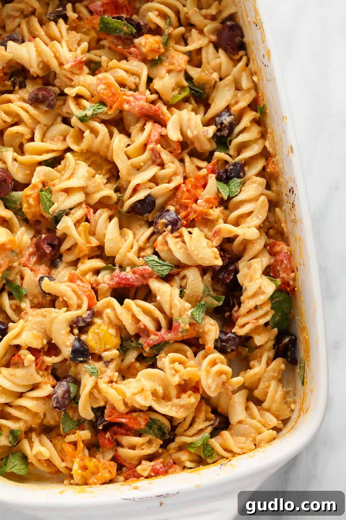 Delicious and easy baked feta pasta with roasted tomatoes, feta, and fresh herbs. Baked feta pasta in a rustic casserole dish, garnished with fresh basil and Kalamata olives.