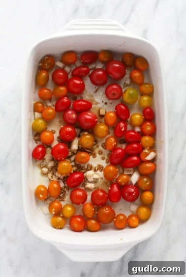 Roasted Feta Tomato Pasta Perfection 4 Roasted cherry tomatoes, garlic, and onion in a white baking dish before adding feta.
