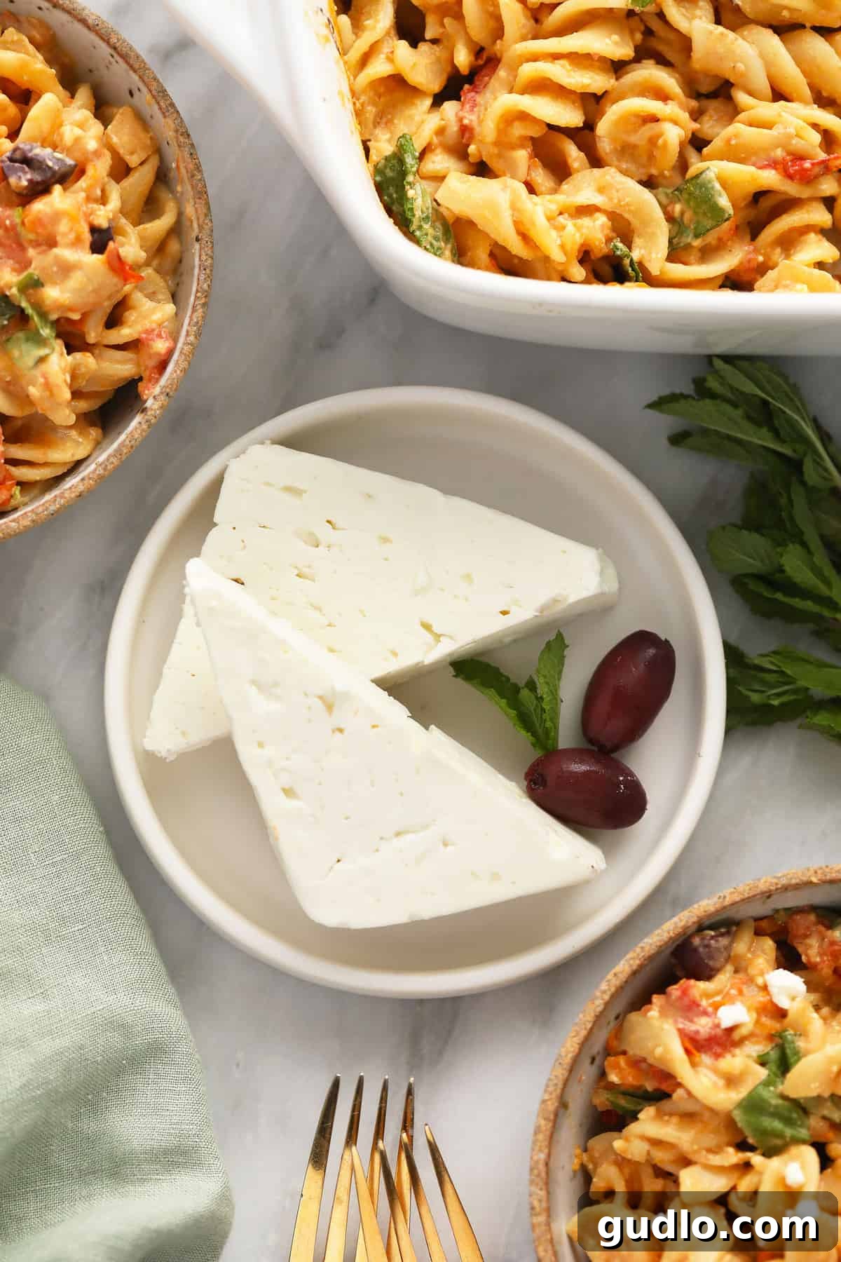 High-quality block of feta cheese, a key ingredient for baked feta pasta. A perfectly white block of feta cheese resting on a small plate, ready for baking.