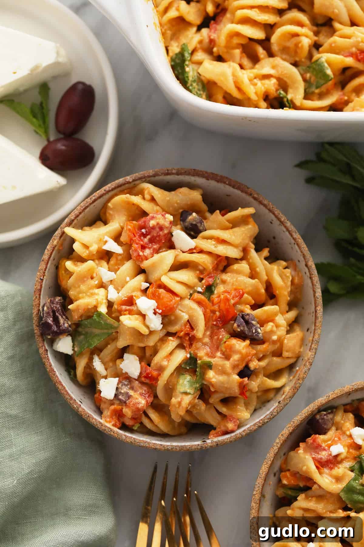 Baked Feta Pasta served in a bowl, showcasing its rich texture. A generous serving of baked feta pasta with roasted tomatoes and fresh basil in a rustic ceramic bowl, ready to be savored.