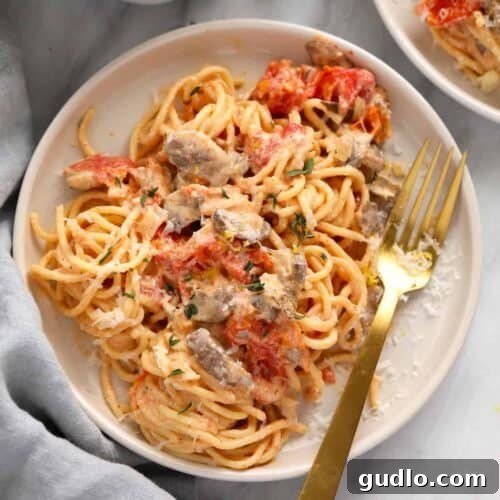 A baked plate of cream cheese pasta with roasted tomatoes and herbs.