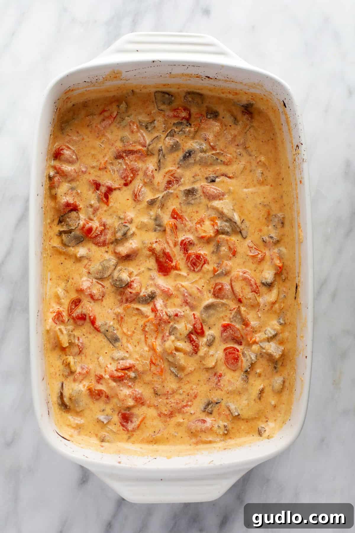Creamy Baked Pasta Sauce Mixed to Perfection The baked cream cheese pasta sauce, now expertly mixed into a smooth, creamy consistency with burst tomatoes and tender mushrooms, ready for the cooked pasta.