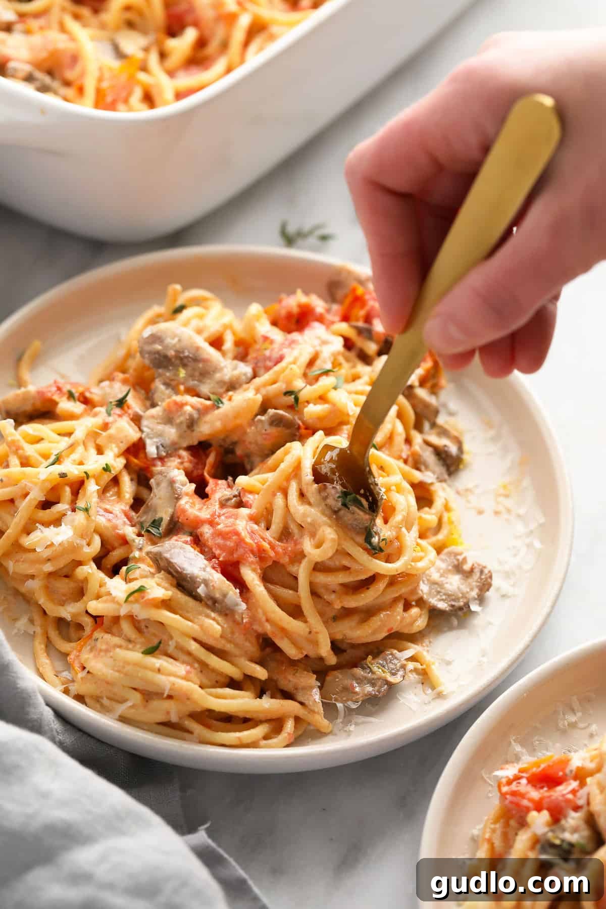 Creamy Baked Cream Cheese Pasta on a Fork A fork twirling a generous portion of baked cream cheese pasta, showcasing the creamy sauce and tender spaghetti strands, inviting a taste.