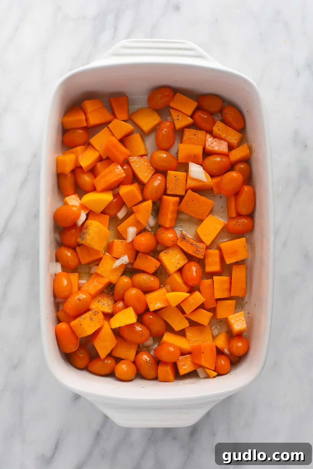 Prepping Roasted Butternut Squash Pasta Ingredients Butternut squash, cherry tomatoes, and onion arranged in a casserole dish before baking