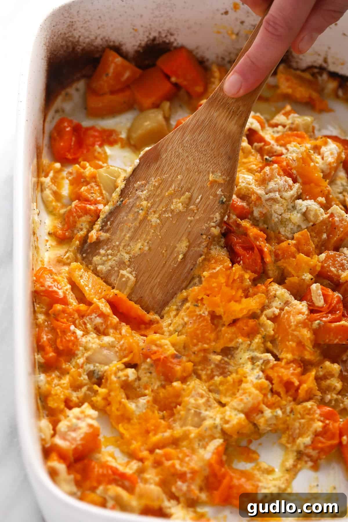 Crafting the Creamy Butternut Squash Sauce Mashing roasted butternut squash, tomatoes, garlic, and Boursin cheese together in a casserole dish to create a creamy sauce